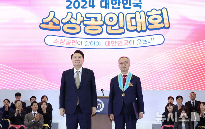 [고양=뉴시스] 조수정 기자 = 윤석열 대통령이 31일 경기 고양시 일산 킨텍스에서 열린 2024 대한민국 소상공인대회 개막식에 참석해 듀팡과자점 서용필 대표에게 은탑산업훈장을 수여한 뒤 기념촬영을 하고 있다. 2024.10.31. chocrystal@newsis.com