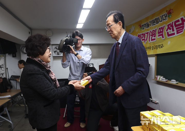 [서울=뉴시스] 김근수 기자 = 이선재(오른쪽) 일성여자중고등학교 교장이 12일 서울 마포구 일성여자중고등학교에서 열린 만학도 수능시험 합격 기원 떡 전달식에서 일성여자고등학교 수능 최고령 응시자 임태수 씨(83세)에게 수능 합격 기원 떡을 전달하고 있다. 2024.11.12. ks@newsis.com