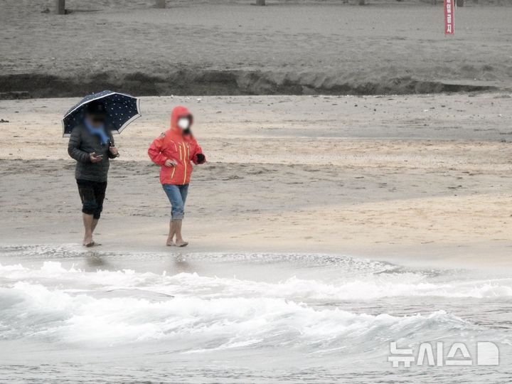 [제주=뉴시스] 오영재 기자 = 제주시 이호테우해변에서 우산과 우비를 쓴 방문객들이 맨발 걷기 활동인 '어싱'을 하고 있다. (사진=뉴시스DB) oyj4343@newsis.com  