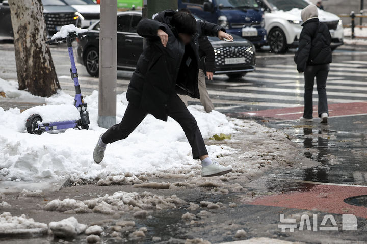 [서울=뉴시스] 정병혁 기자 = 28일 서울 강남구 뱅뱅사거리 인근 배수로가 낙엽과 눈으로 막히면서 물이 고여있는 횡단보도를 한 시민이 뛰어넘고 있다. 2024.11.28. jhope@newsis.com