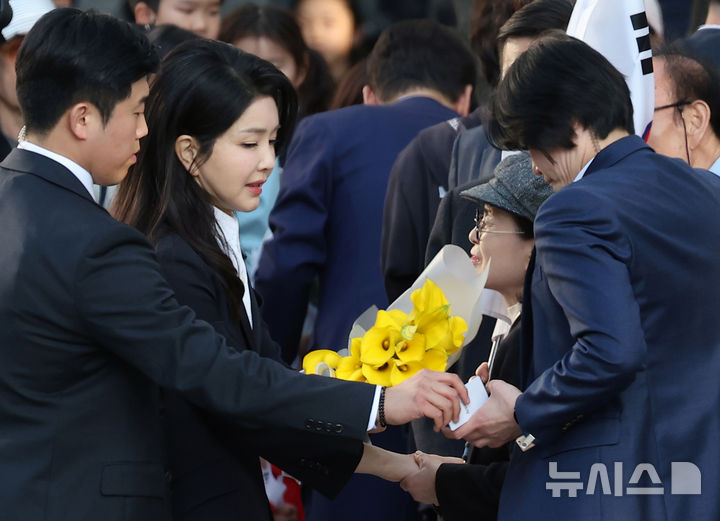 [서울=뉴시스] 최동준 기자 = 윤석열 전 대통령 부인 김건희 여사가 11일 서울 서초구 사저로 들어서며 마중 나온 관계자들에게 꽃다발을 받고 있다. (공동취재) 2025.04.11. photo@newsis.com