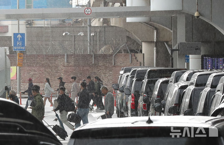 [제주=뉴시스] 우장호 기자 = 강한 비바람이 부는 9일 오전 제주국제공항에서 제주에 도착한 이용객들이 비를 피해 이동하고 있다. 2025.05.09. woo1223@newsis.com