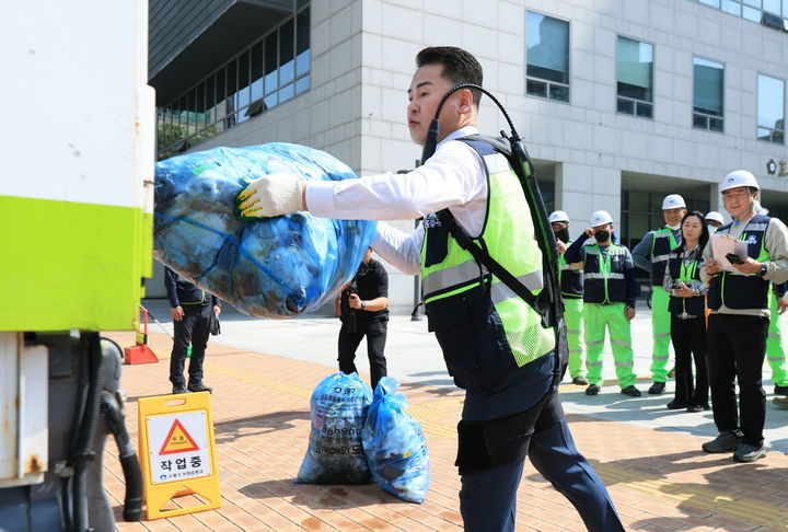 [서울=뉴시스] 오언석 도봉구청장이 ‘입는 로봇’을 입고 쓰레기를 청소차에 옮기고 있다. 2025.05.15. (사진=도봉구 제공) *재판매 및 DB 금지