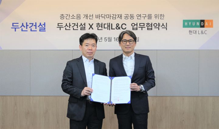 [서울=뉴시스] 신홍철 두산건설 상무(오른쪽)와 성재용 현대L&C 상무가 16일 층간소음 개선을 위한 바닥 마감재 공동 연구 업무협약(MOU)을 체결한 뒤 기념촬영을 하고 있다. 2025.05.16. (사진=두산건설 제공) photo@newsis.com *재판매 및 DB 금지