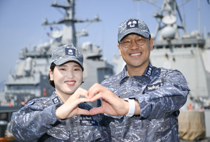 [서울=뉴시스] 율곡이이함 기관장 임재우 중령(진)과 정조대왕함 주기실장 김보아 소령이 율곡이이함(우측) 함수갑판에서 '손하트' 포즈를 취하고 있다. (사진=해군 제공) 2025.05.20. photo@newsis.com *재판매 및 DB 금지