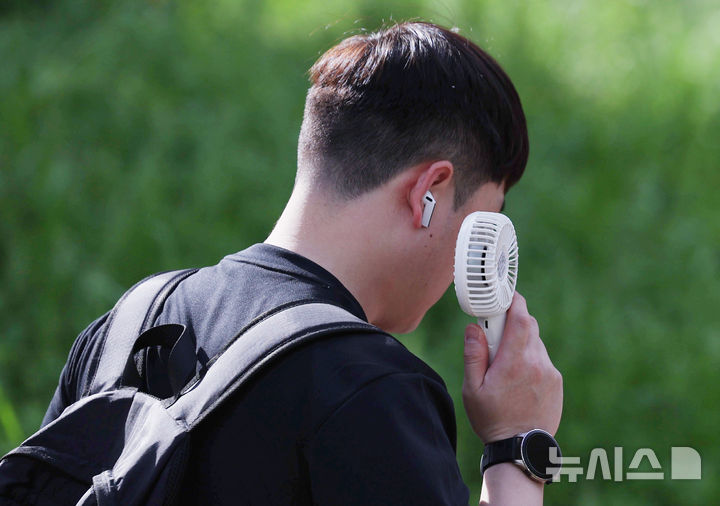 [서울=뉴시스] 김진아 기자 = 여름 기운이 돌기 시작하는 절기 '소만'인 21일 서울 종로구 일대에서 반팔을 입은 시민이 손선풍기를 사용하며 출근하고 있다. 2025.05.21. bluesoda@newsis.com